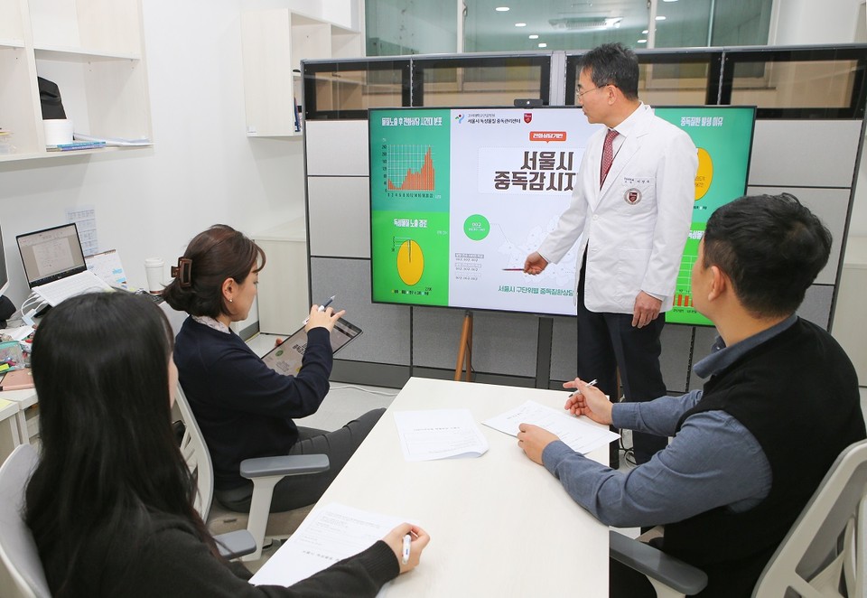 고대안암병원 서울시 독성물질 중독관리센터 이성우 센터장이 화면을 보고 설명하며, 연구원들과 중독감시체계 구축 관련 회의를 진행하고 있다.