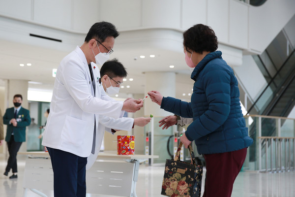 배장호 의료원장과 김훈 기획조정실장이 병원 로비에서 화이트데이 사탕나눔 이벤트 진행하고 있다.